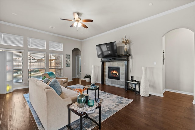 living room featuring dark hardwood / wood-style flooring, crown molding, and a tile fireplace