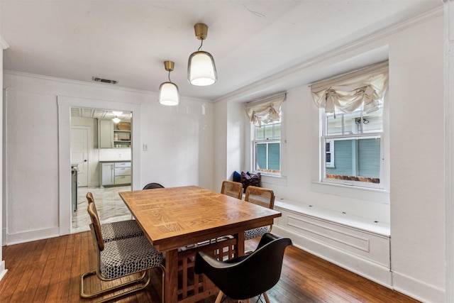 dining area with wood-type flooring and crown molding