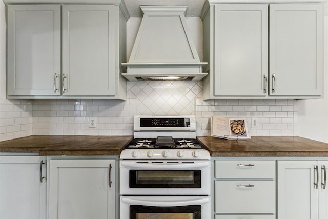 kitchen with custom exhaust hood, white cabinets, double oven range, and tasteful backsplash