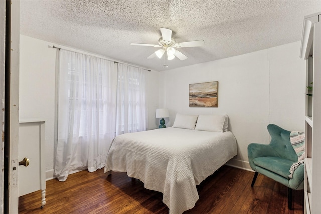 bedroom with a textured ceiling, ceiling fan, and dark hardwood / wood-style floors