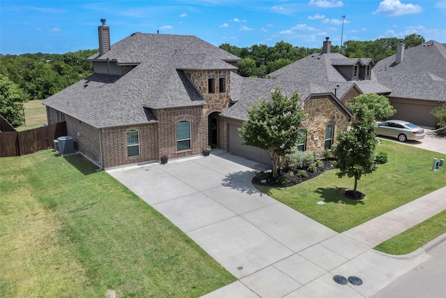 view of front of home featuring central AC unit, a front lawn, and a garage