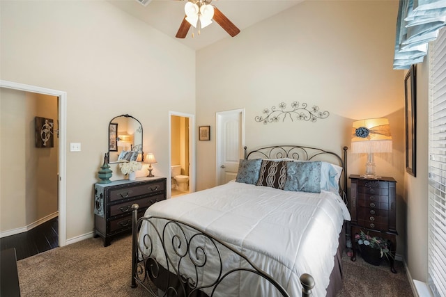 carpeted bedroom featuring ceiling fan, connected bathroom, and a towering ceiling