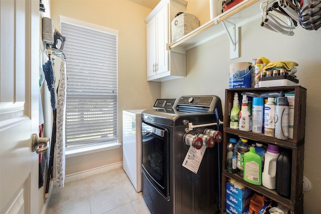 clothes washing area featuring washer and dryer, cabinets, and light tile patterned floors