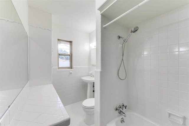 bathroom featuring toilet, tiled shower / bath combo, and tile walls