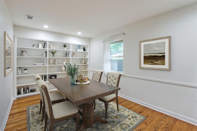 dining space with built in shelves and light hardwood / wood-style floors