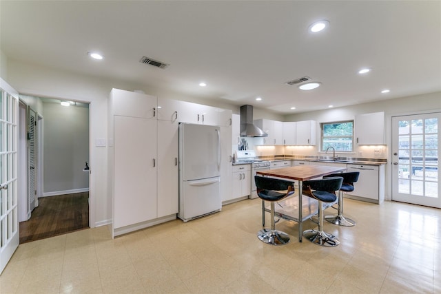 kitchen featuring sink, white appliances, white cabinets, and wall chimney exhaust hood