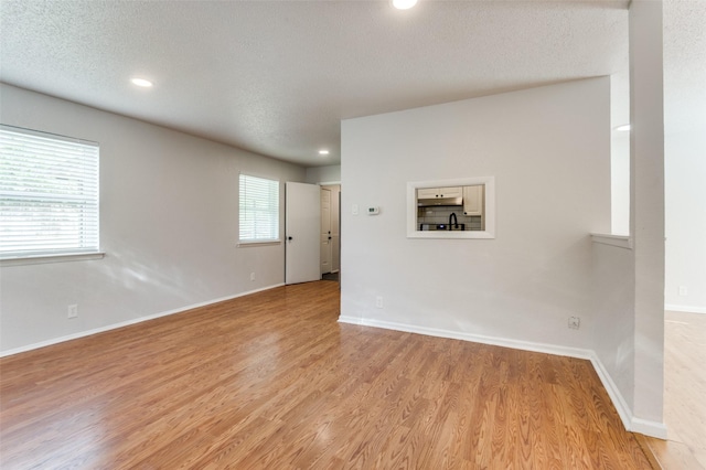 spare room with light hardwood / wood-style floors and a textured ceiling