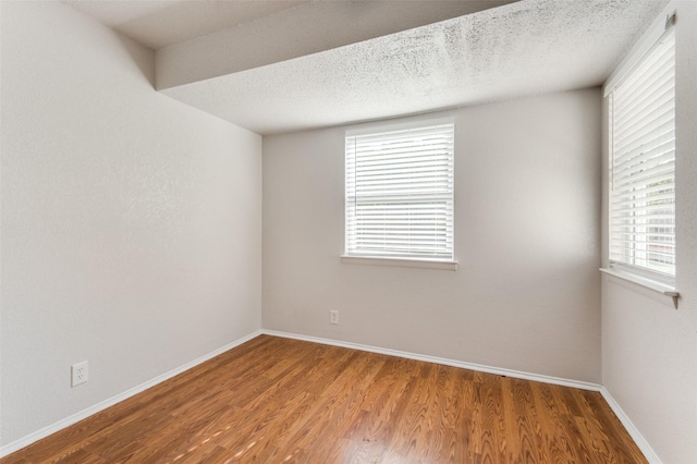 empty room featuring a textured ceiling and hardwood / wood-style flooring