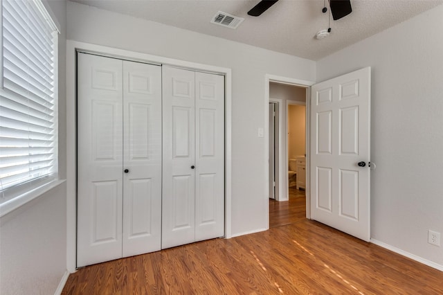 unfurnished bedroom with a textured ceiling, ceiling fan, a closet, and light hardwood / wood-style flooring