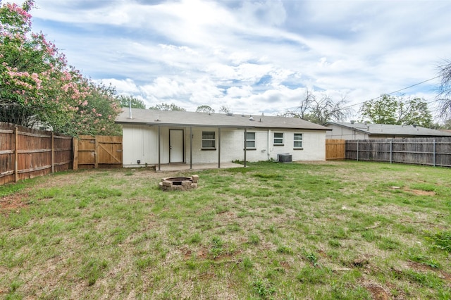 back of house with a lawn and an outdoor fire pit