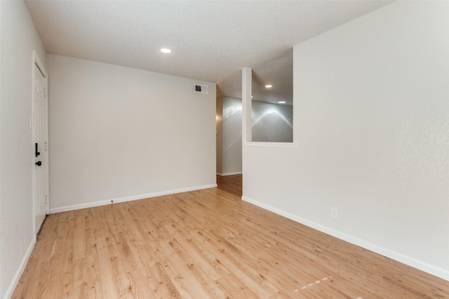 spare room with a textured ceiling and light hardwood / wood-style flooring