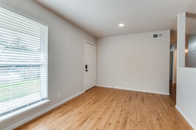 empty room featuring a textured ceiling and light hardwood / wood-style floors