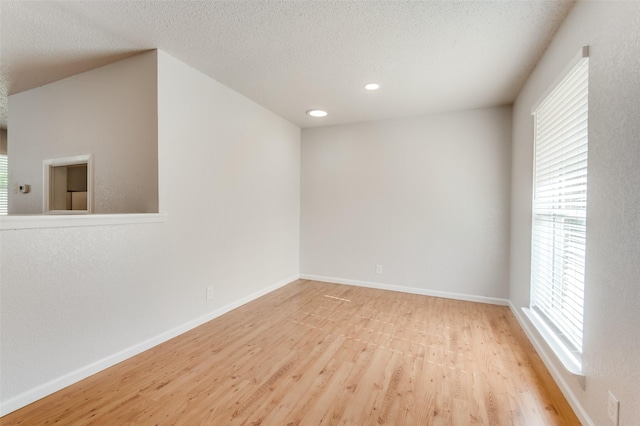 empty room with light wood-type flooring and a textured ceiling