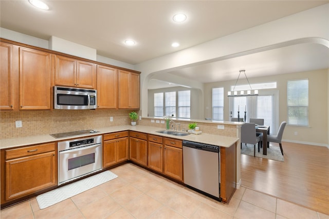 kitchen featuring decorative light fixtures, sink, appliances with stainless steel finishes, and kitchen peninsula