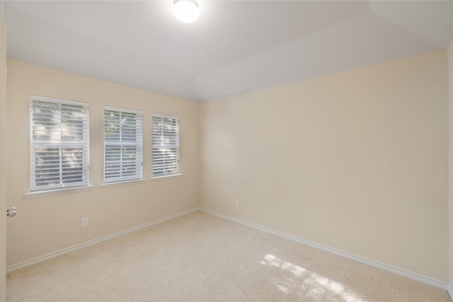 empty room with light colored carpet and vaulted ceiling