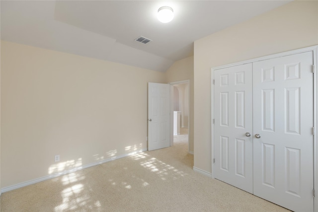 unfurnished bedroom with lofted ceiling, a closet, and light carpet