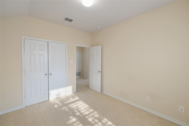 unfurnished bedroom with a closet, light carpet, and vaulted ceiling