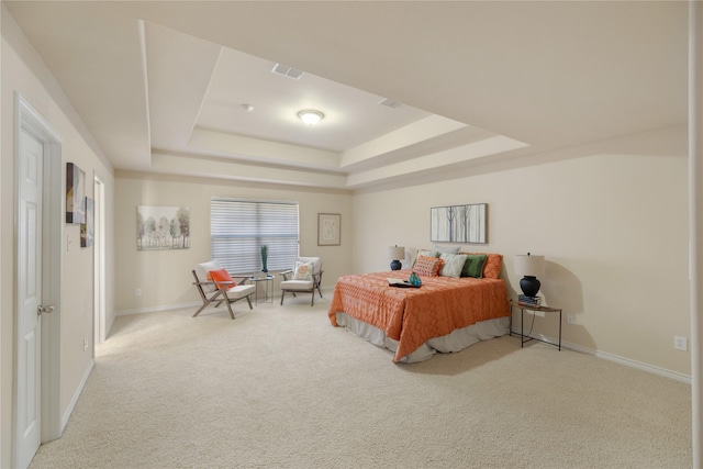 bedroom with light colored carpet and a tray ceiling