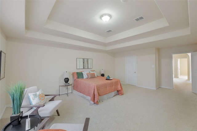 bedroom featuring light carpet and a tray ceiling