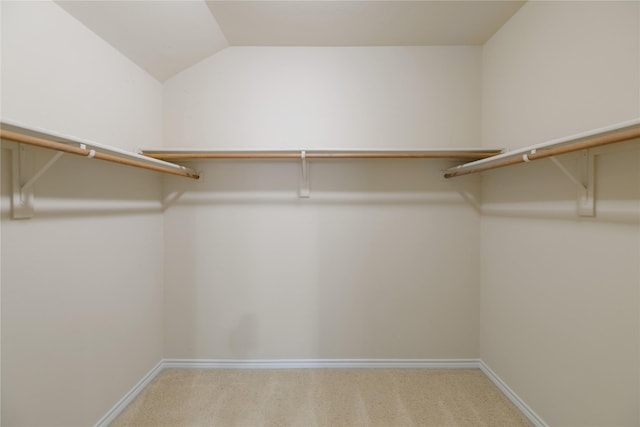 spacious closet featuring lofted ceiling and light colored carpet