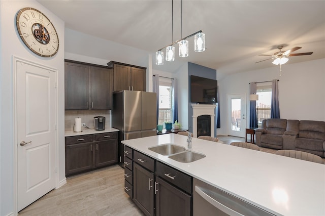 kitchen with a wealth of natural light, dark brown cabinetry, appliances with stainless steel finishes, decorative light fixtures, and sink