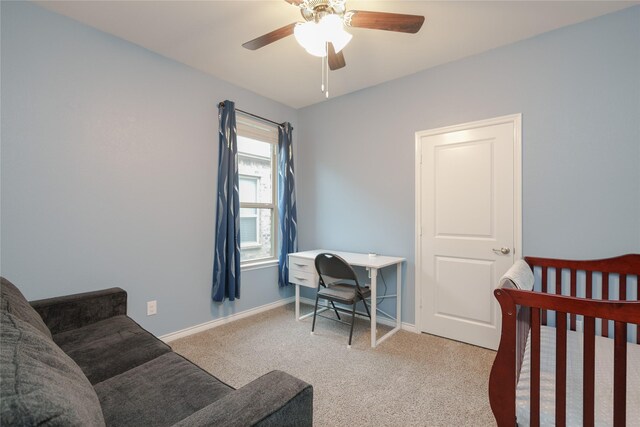 carpeted bedroom with ceiling fan and a crib