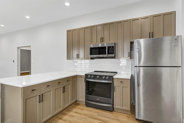 kitchen with appliances with stainless steel finishes, light hardwood / wood-style flooring, kitchen peninsula, and tasteful backsplash