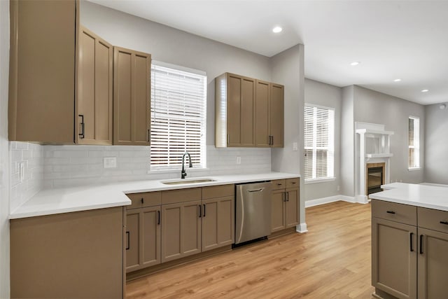 kitchen with light wood-type flooring, decorative backsplash, stainless steel dishwasher, and sink