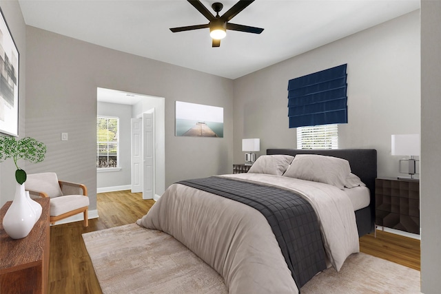 bedroom featuring ceiling fan, multiple windows, and hardwood / wood-style flooring