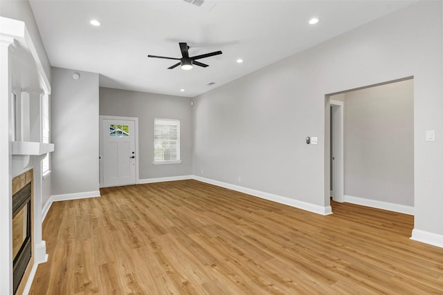 unfurnished living room with ceiling fan, light hardwood / wood-style flooring, and a tiled fireplace