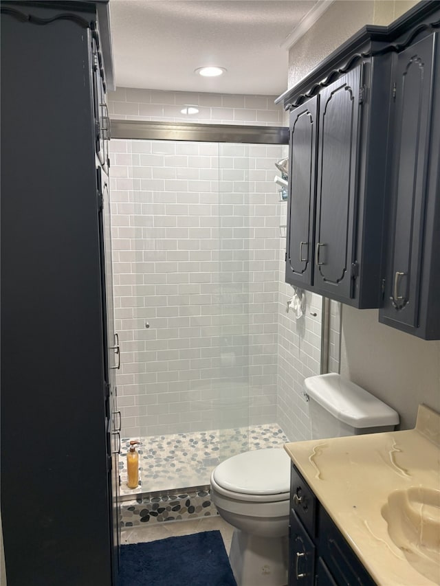 bathroom featuring toilet, vanity, tile patterned flooring, a textured ceiling, and a tile shower