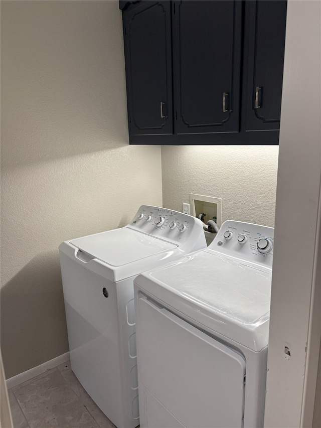 laundry area with cabinets, light tile patterned flooring, and washer and clothes dryer