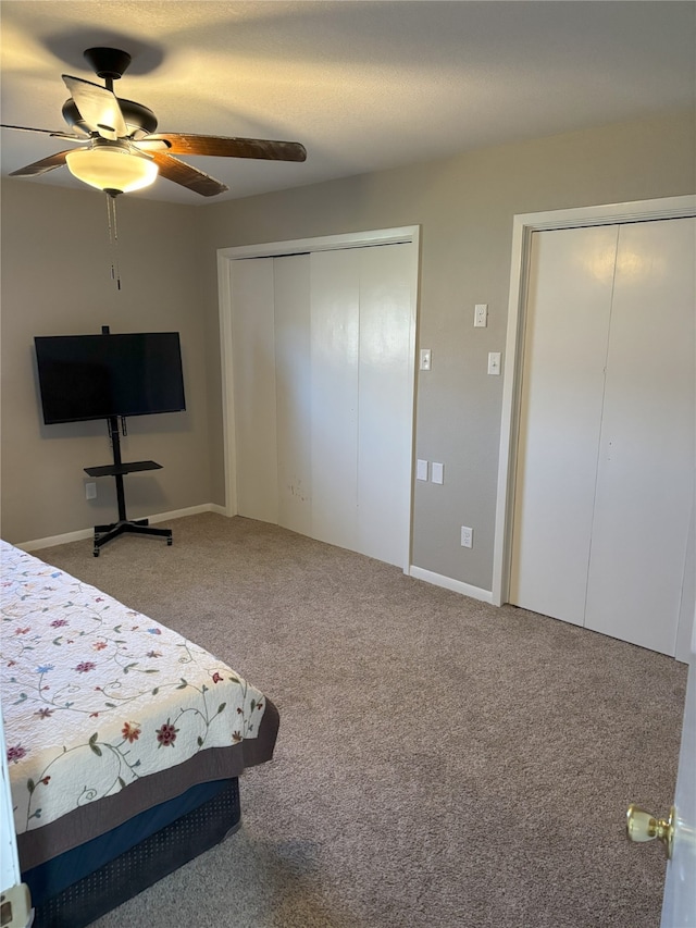 unfurnished bedroom with ceiling fan, carpet, and two closets