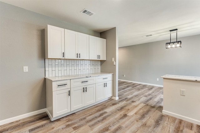 kitchen with pendant lighting, light hardwood / wood-style floors, and white cabinets