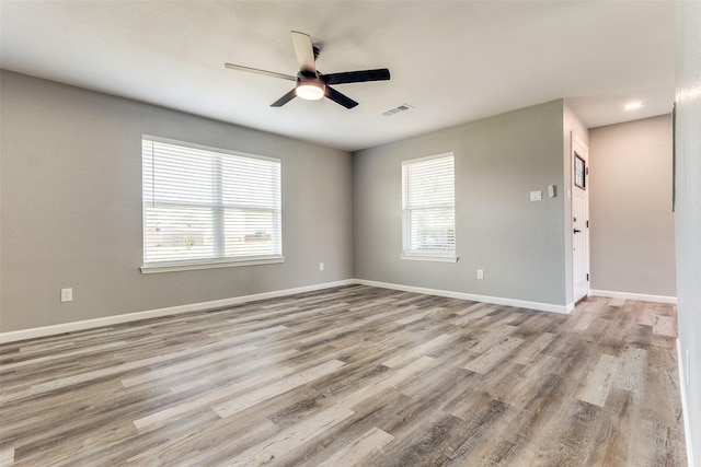 spare room featuring ceiling fan, a wealth of natural light, and light hardwood / wood-style flooring