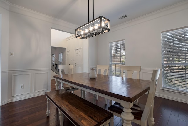 dining area featuring dark hardwood / wood-style flooring, ornamental molding, and an inviting chandelier