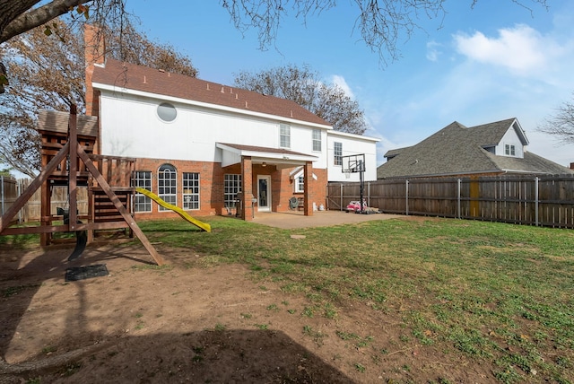 rear view of property featuring a yard, a patio, and a playground