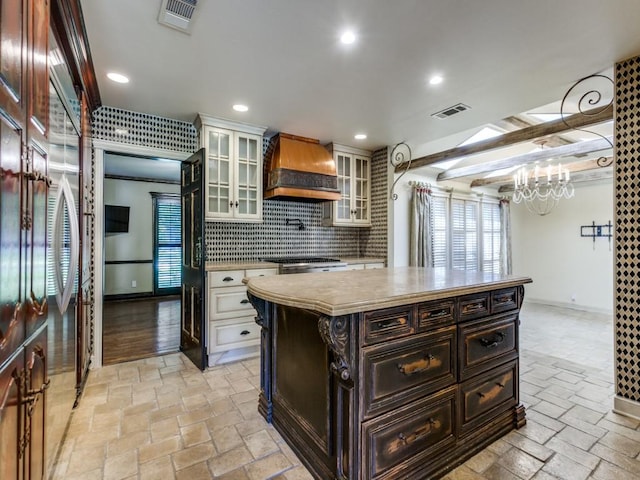 kitchen featuring white cabinetry, custom exhaust hood, decorative backsplash, a center island, and beamed ceiling