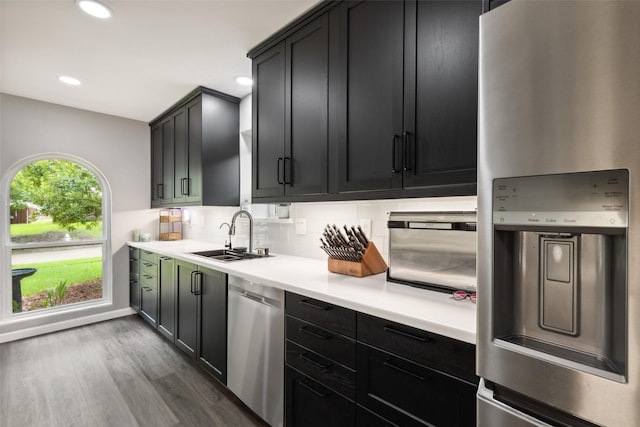 kitchen with dark wood-type flooring, sink, decorative backsplash, and appliances with stainless steel finishes