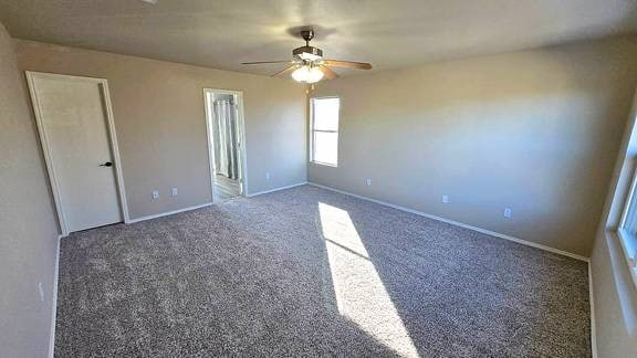 unfurnished bedroom featuring dark colored carpet and ceiling fan