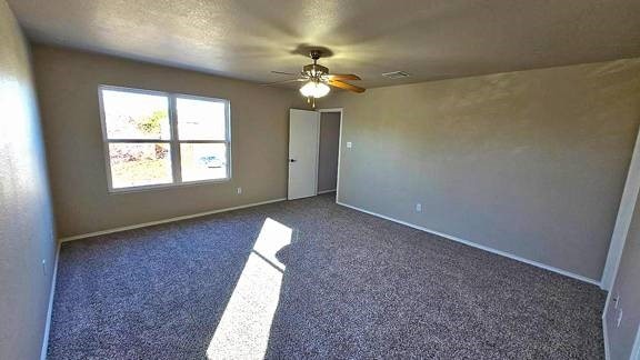 carpeted spare room with ceiling fan