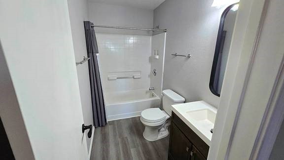 full bathroom with hardwood / wood-style floors, toilet, bathtub / shower combination, and vanity