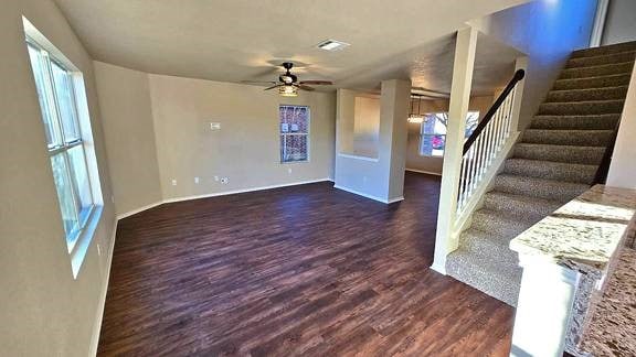 unfurnished living room featuring ceiling fan and dark hardwood / wood-style flooring