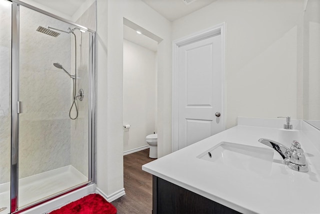 bathroom with toilet, a shower with shower door, hardwood / wood-style floors, and vanity