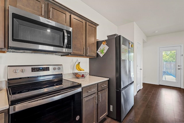 kitchen with dark wood-type flooring, dark brown cabinetry, and appliances with stainless steel finishes