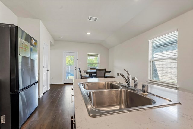 kitchen with dark hardwood / wood-style floors, lofted ceiling, stainless steel fridge, and sink