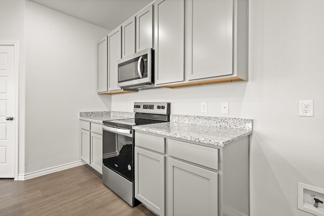 kitchen featuring light stone counters, stainless steel appliances, and hardwood / wood-style floors