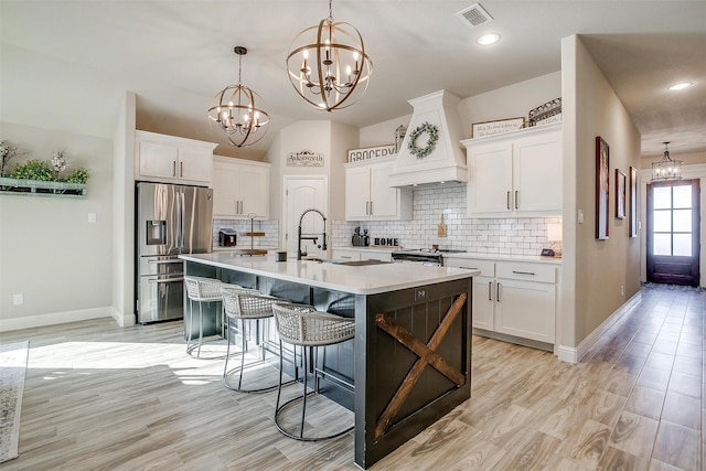 kitchen with stainless steel appliances, white cabinetry, and an island with sink