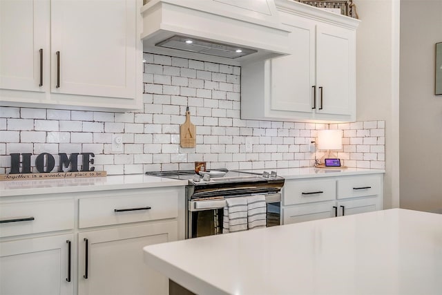 kitchen featuring electric stove, decorative backsplash, white cabinetry, and custom range hood