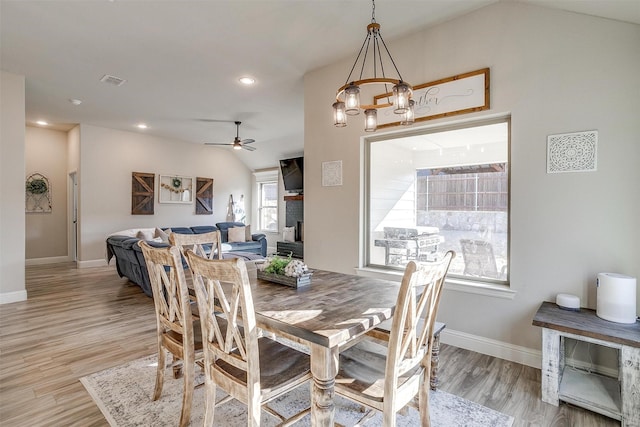 dining room with lofted ceiling, light wood-type flooring, and ceiling fan with notable chandelier